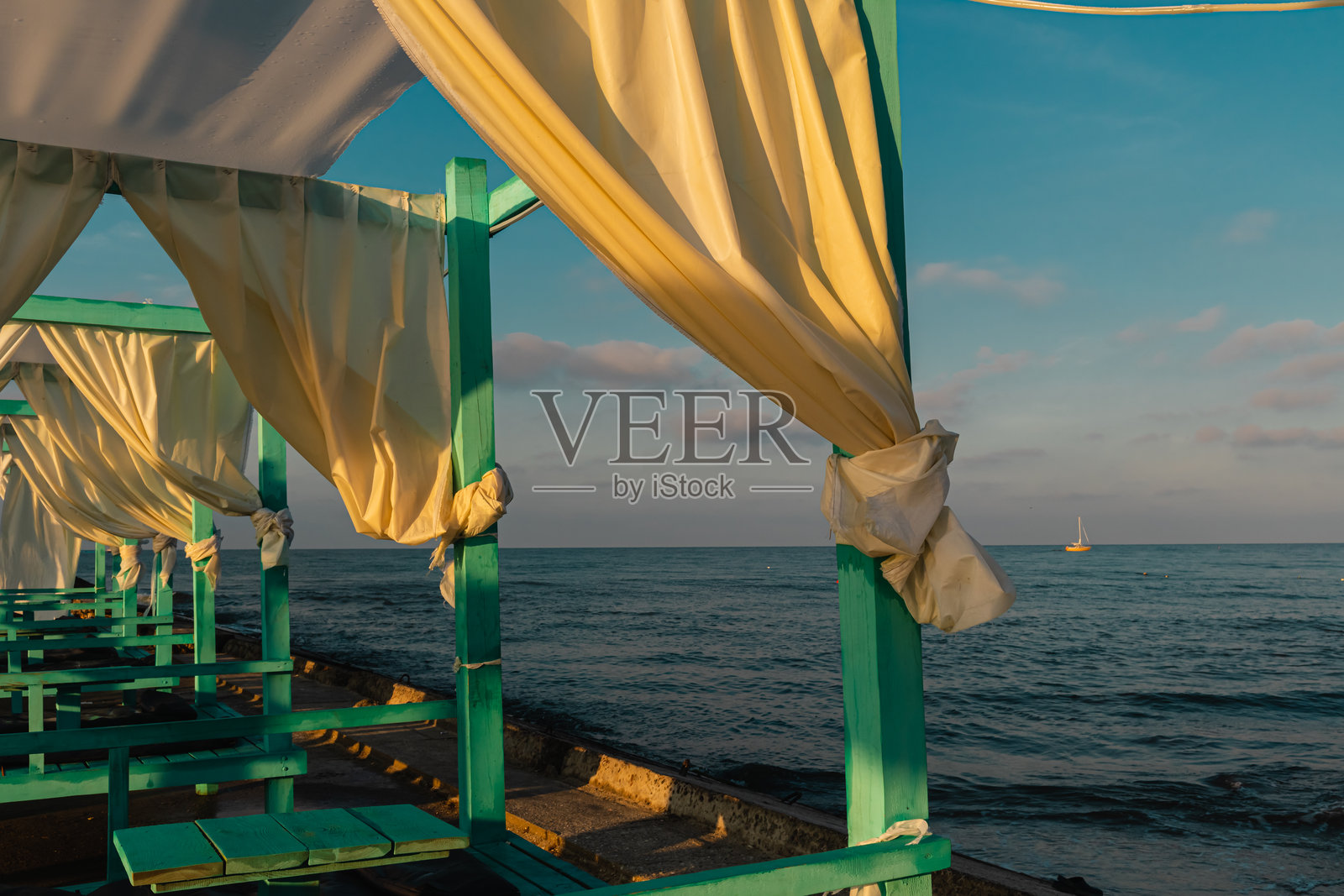 黑海海岸的绿松石色木屋，阳光透过轻薄的窗帘洒入室内。照片摄影图片