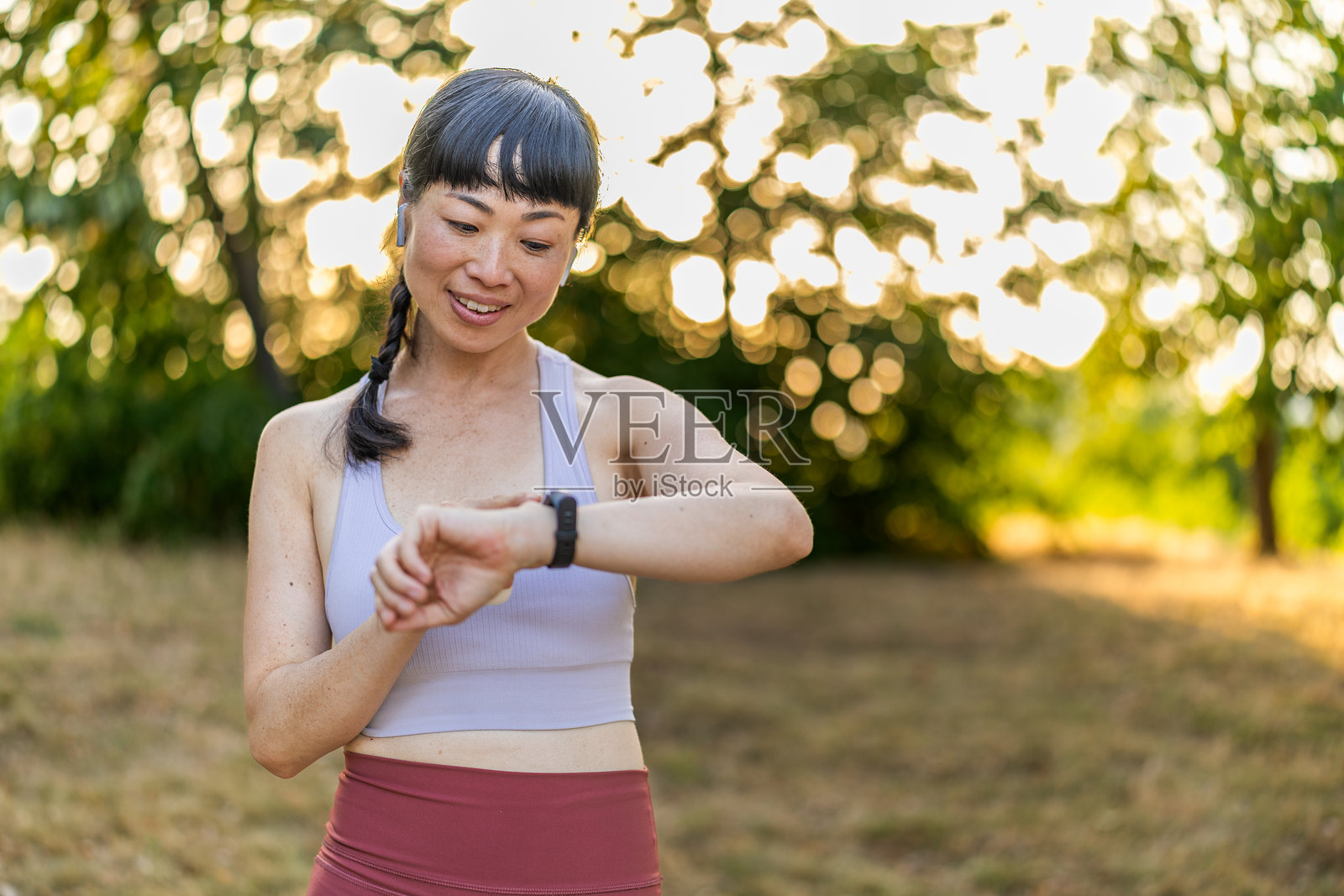 穿着运动服的日本跑者在公园里跑步，享受新鲜空气，提升并检查她的心血管健康。照片摄影图片