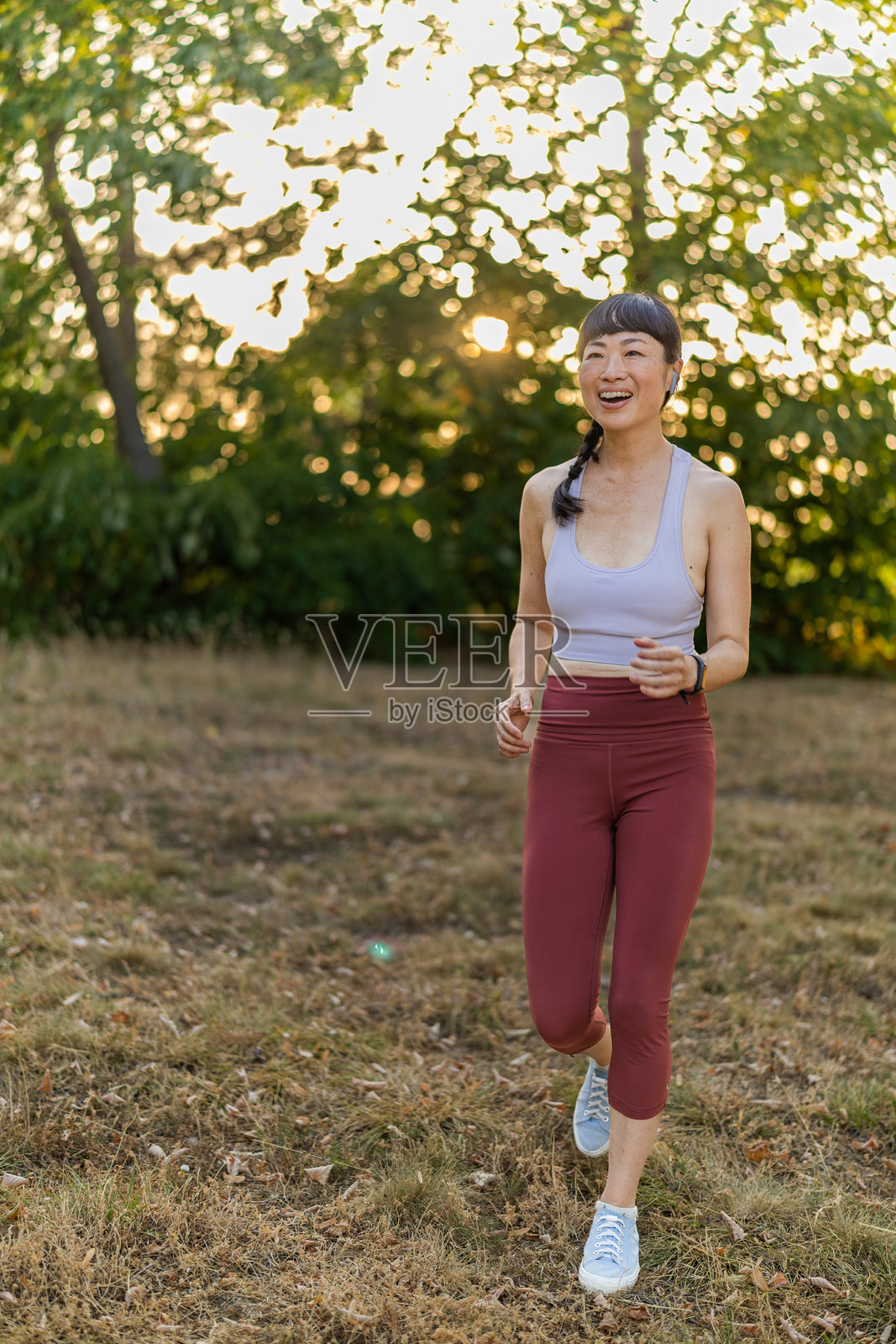 美丽的日本跑者在早晨的公园里微笑着跑步的特写镜头。照片摄影图片