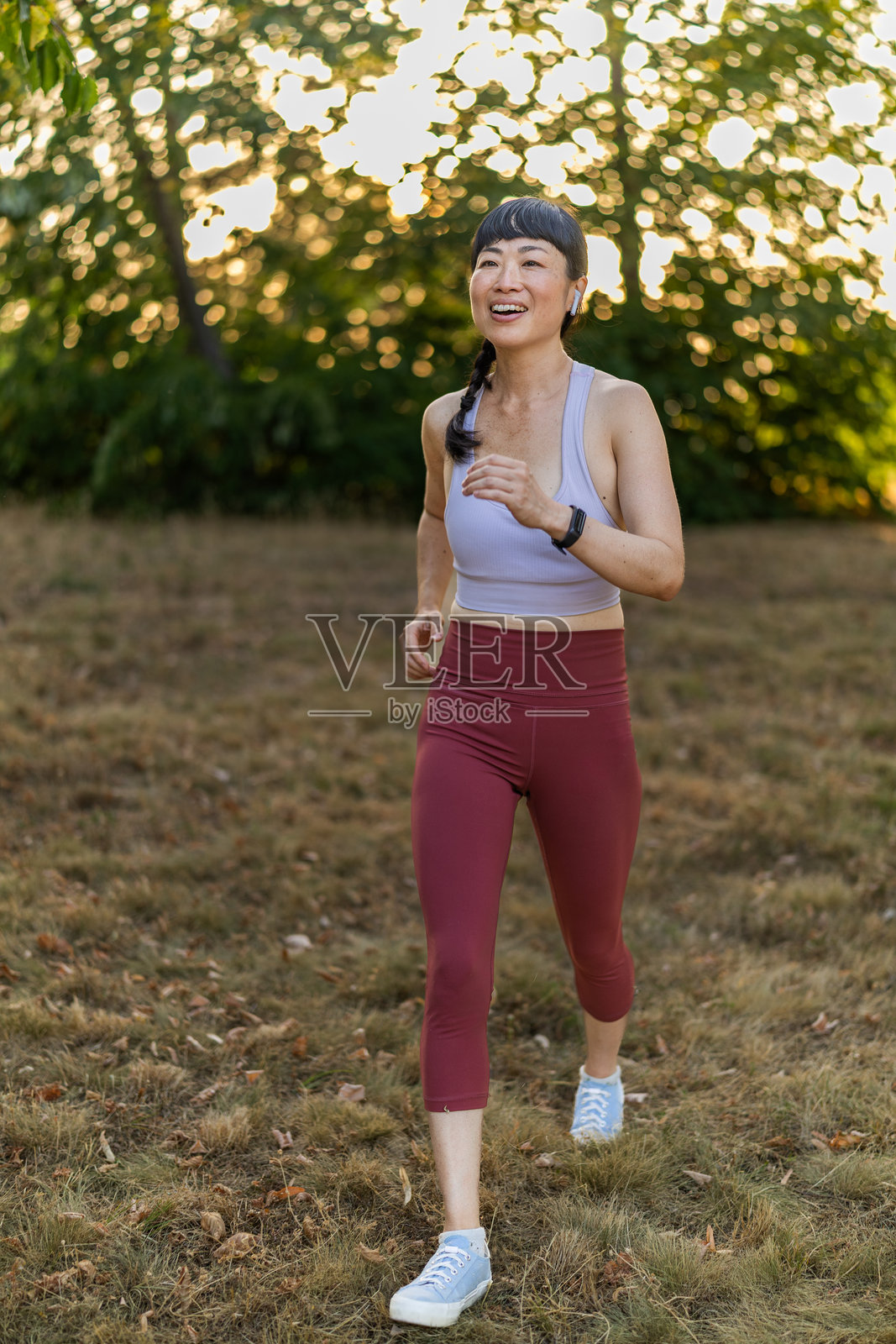 美丽的日本跑者在早晨的公园里微笑着跑步的特写镜头。照片摄影图片