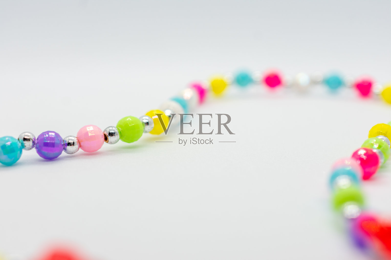 五彩斑斓的项链，串有许多不同颜色的珠子。这些珠子大小和颜色各异，排列成一条线。项链看起来是由玻璃珠制成的，非常美丽。照片摄影图片
