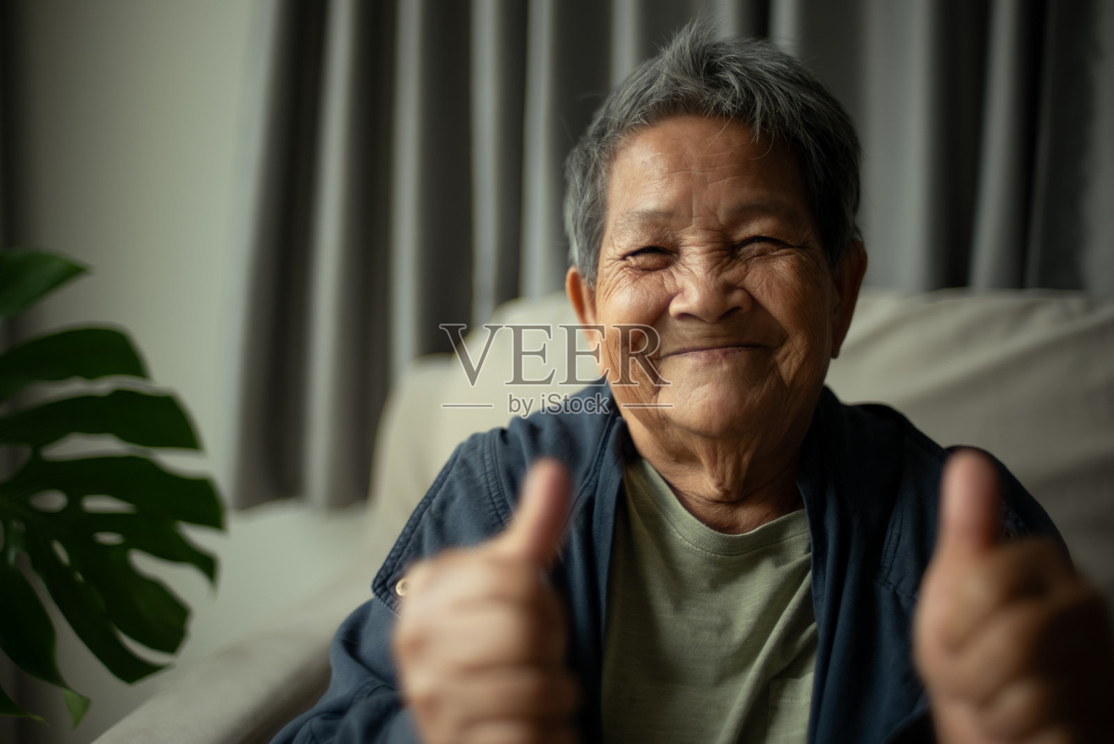 一位老年女性竖起大拇指表示支持。照片摄影图片