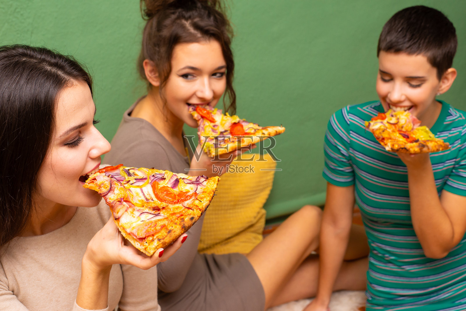 三位年轻快乐的女性在吃披萨照片摄影图片