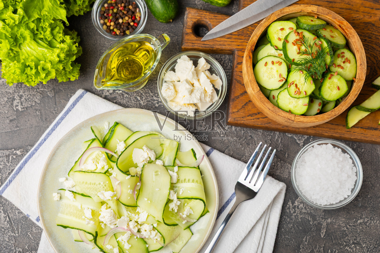 木质背景上的黄瓜沙拉。自制沙拉，盘中有新鲜蔬菜、黄瓜、西红柿、甜椒和生菜。素食春季沙拉。素食饮食。健康饮食。留白以便添加文字。照片摄影图片