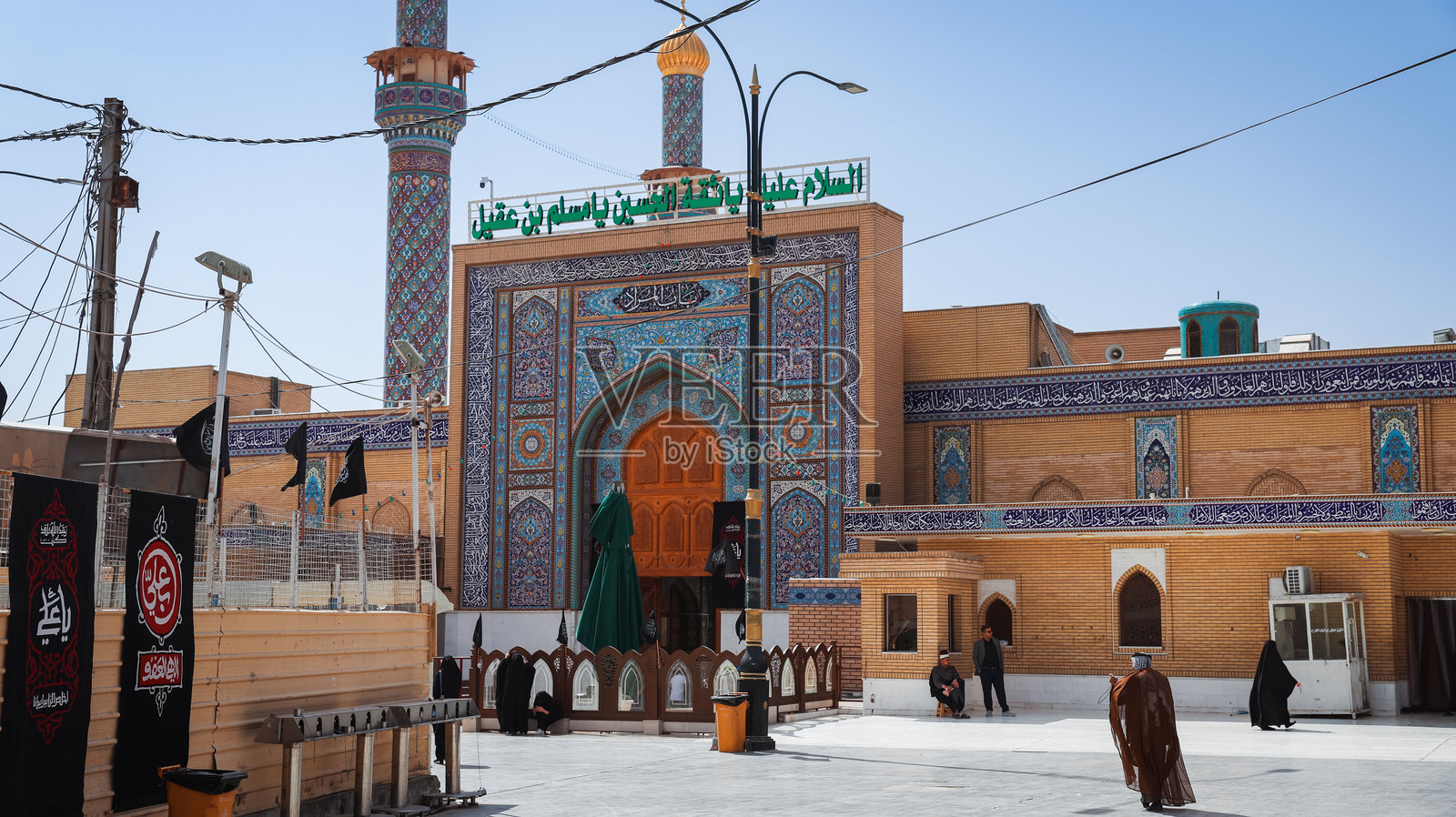 游客在伊拉克库法的一座历史清真寺下聚集，蓝天晴朗。照片摄影图片