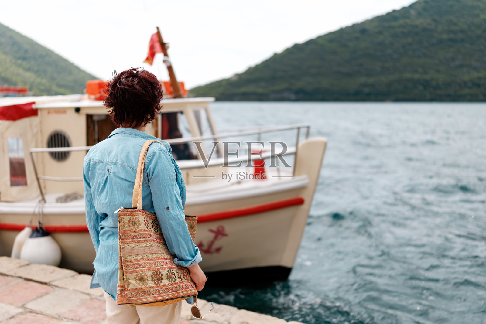 女性游客站在海码头上等待登船游览。照片摄影图片