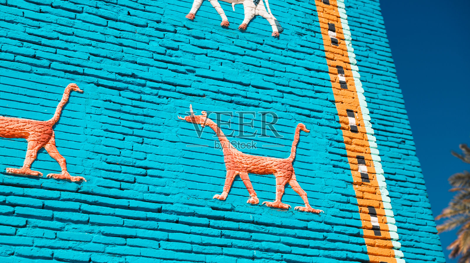 生动的墙面艺术描绘了在伊拉克古巴比伦的动物，背景是晴朗的蓝天。照片摄影图片