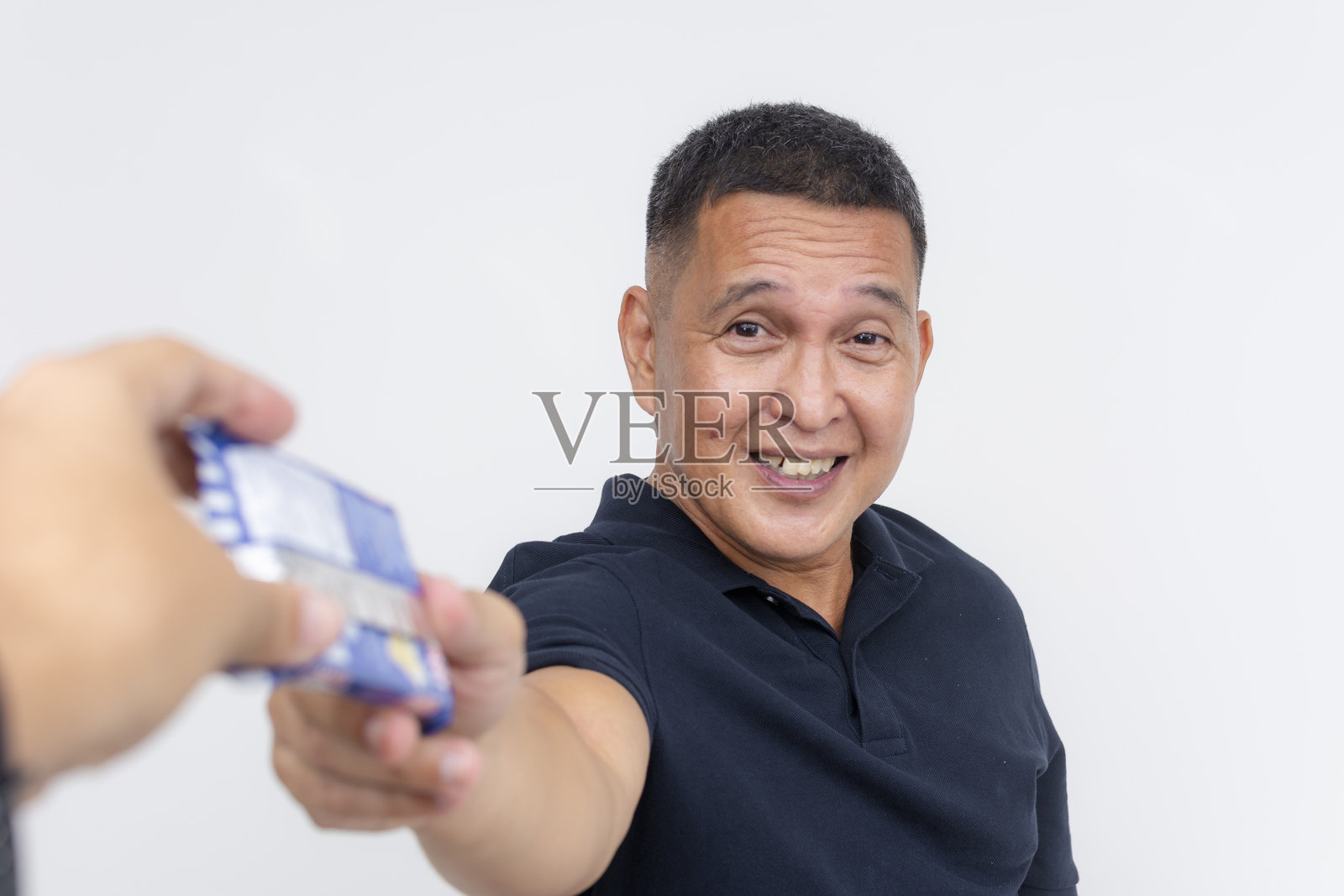 一位快乐且心怀感激的中年男子收到了一包饼干。他在白色背景前快速享用零食并摆姿势。照片摄影图片