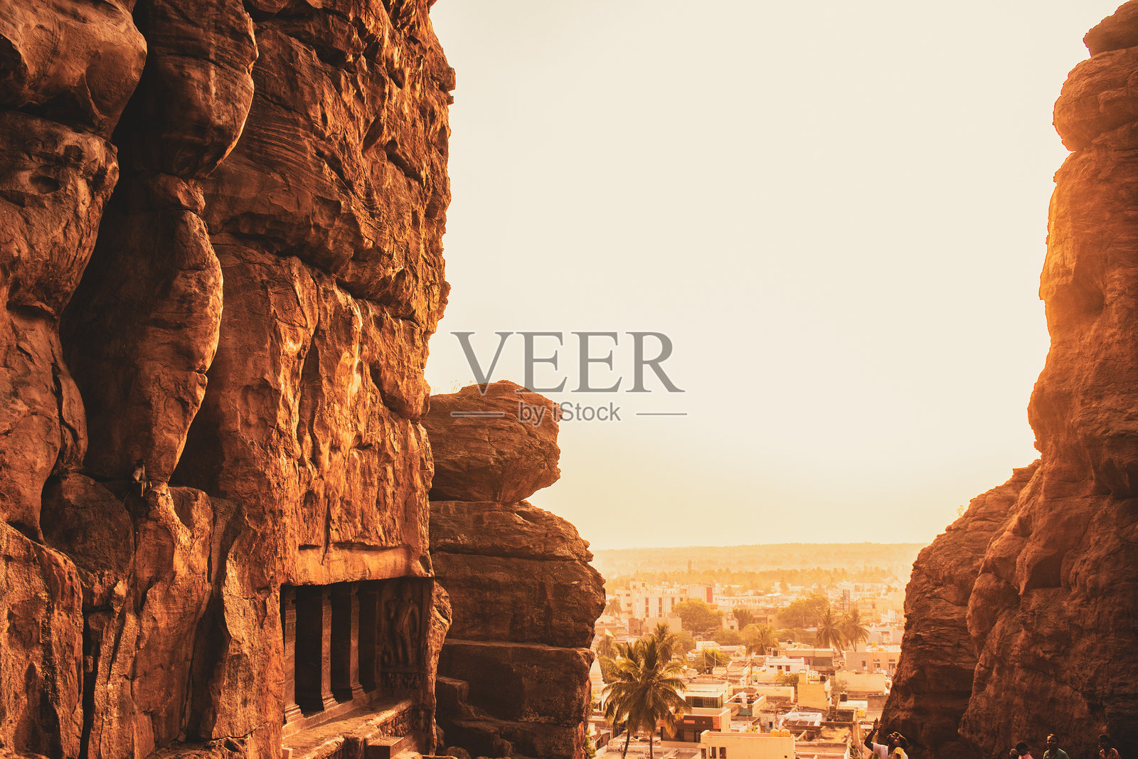 令人惊叹的画面，金色的夕阳光芒洒在卡纳塔克邦巴达米镇上，透过两座崎岖的岩石形成的缝隙，散发出温暖的光辉。照片摄影图片