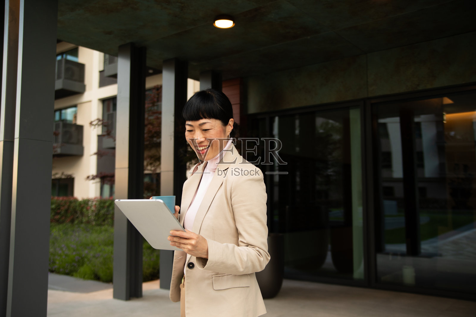 微笑的女商人正在户外办公室使用平板电脑并拿着咖啡照片摄影图片