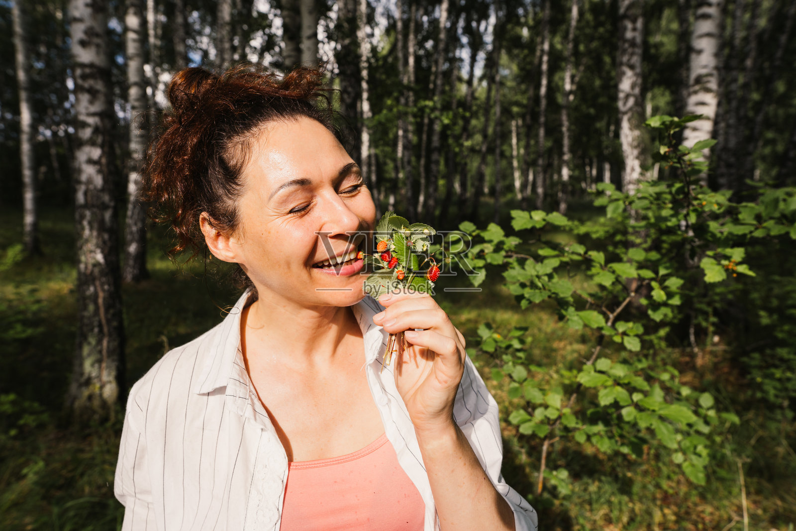 成年女性在森林中享受野生草莓，流露出积极情绪，体现慢生活理念照片摄影图片