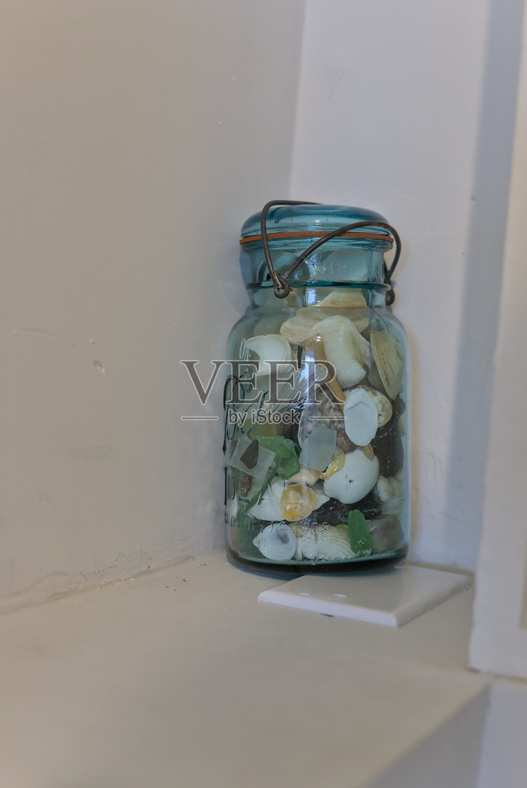 装满各种贝壳的浅蓝色玻璃罐照片摄影图片