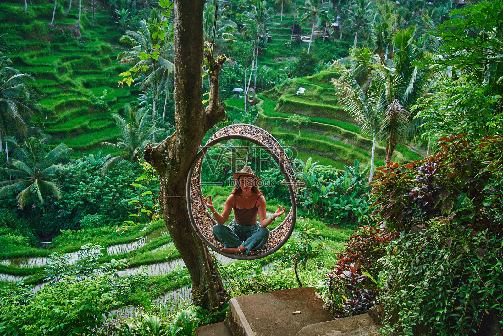 快乐无忧的女性旅行者戴着帽子，享受巴厘岛乌布风景如画的绿色稻田，探索美丽的目的地。照片摄影图片