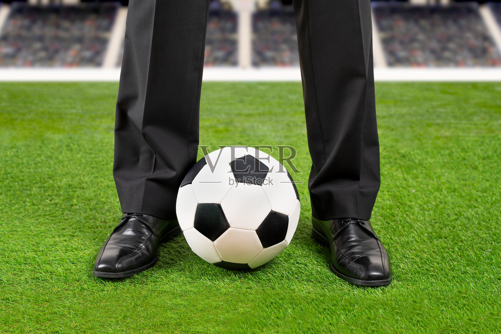 穿着西装的商人在足球场上站着照片摄影图片