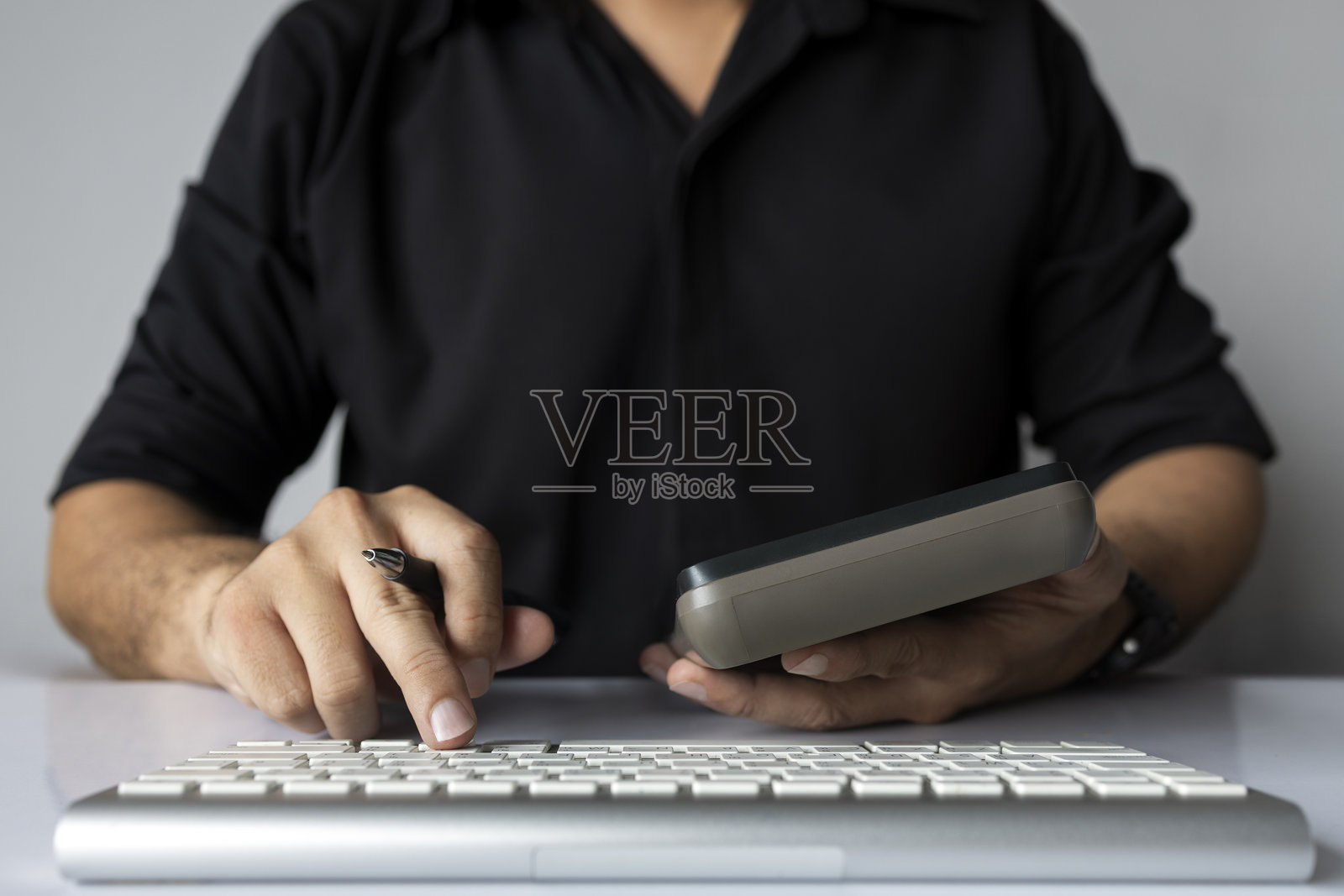 男子手持计算器和钢笔进行商业规划或财务计算照片摄影图片