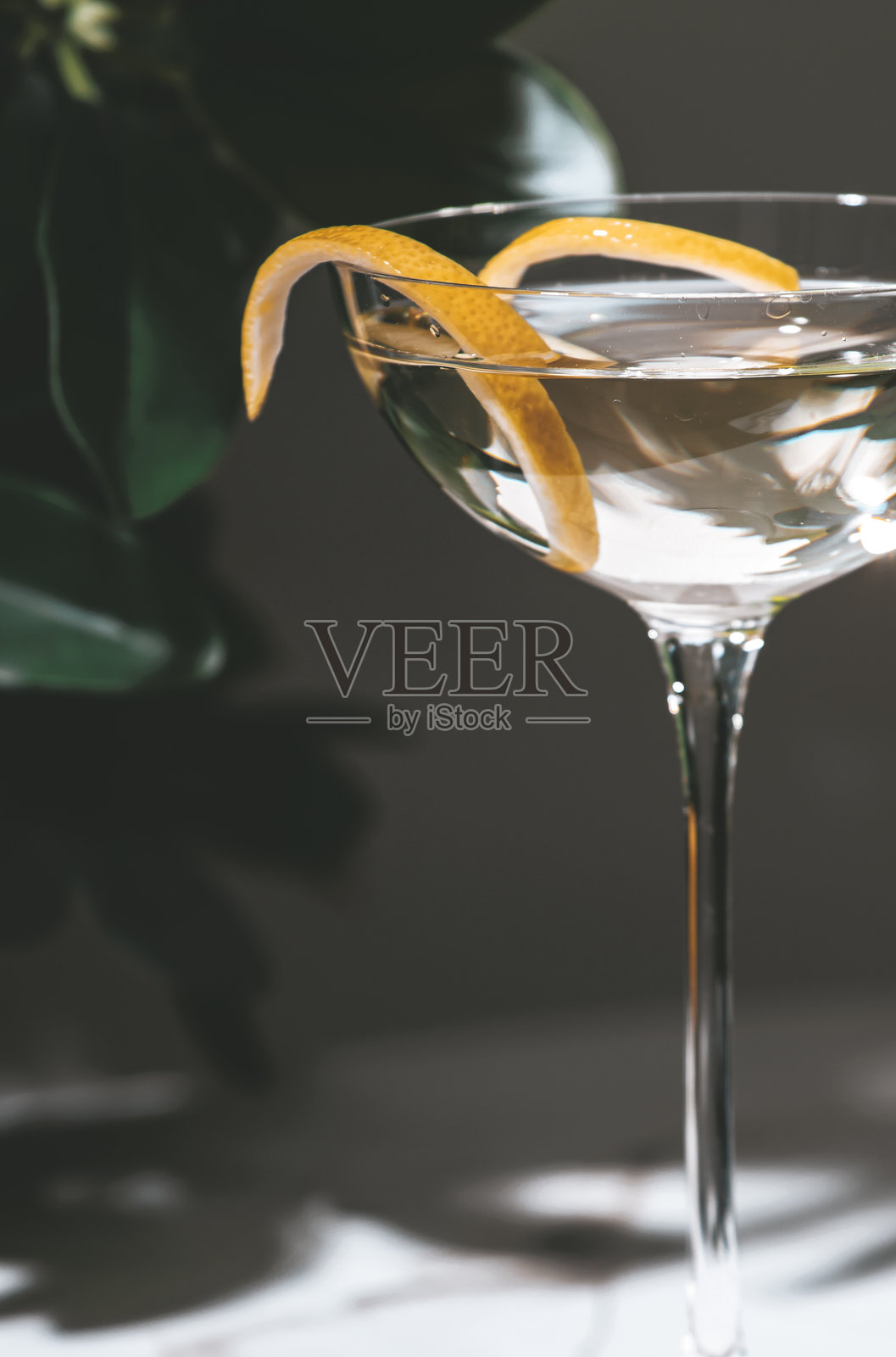 清澈的马提尼鸡尾酒配有柑橘皮的扭曲，优雅地呈现在光滑的酒杯中，营造出精致的饮用体验。照片摄影图片
