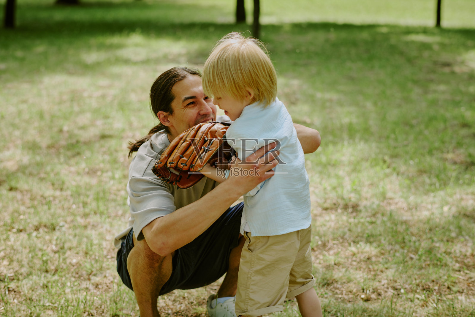 年轻男子在户外公园拥抱小男孩照片摄影图片