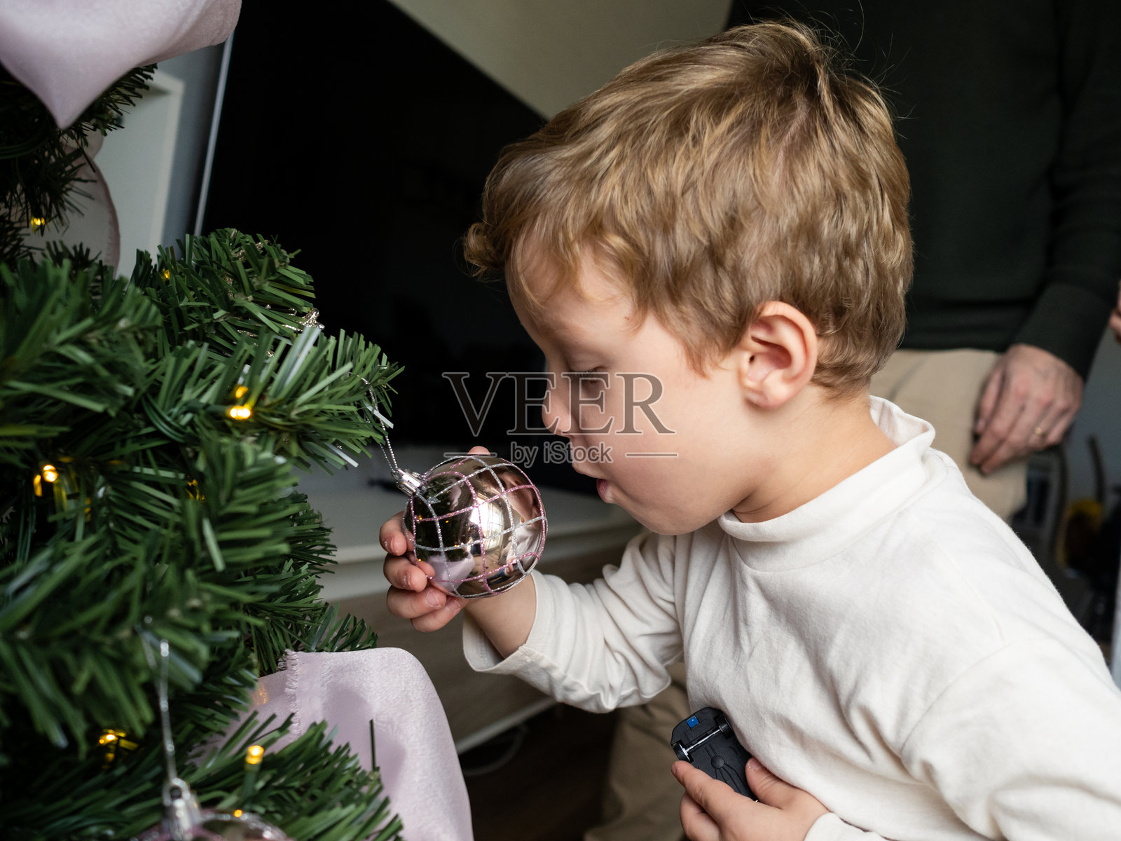 孩子在探索圣诞树装饰，家人则在为节日庆祝活动做准备照片摄影图片