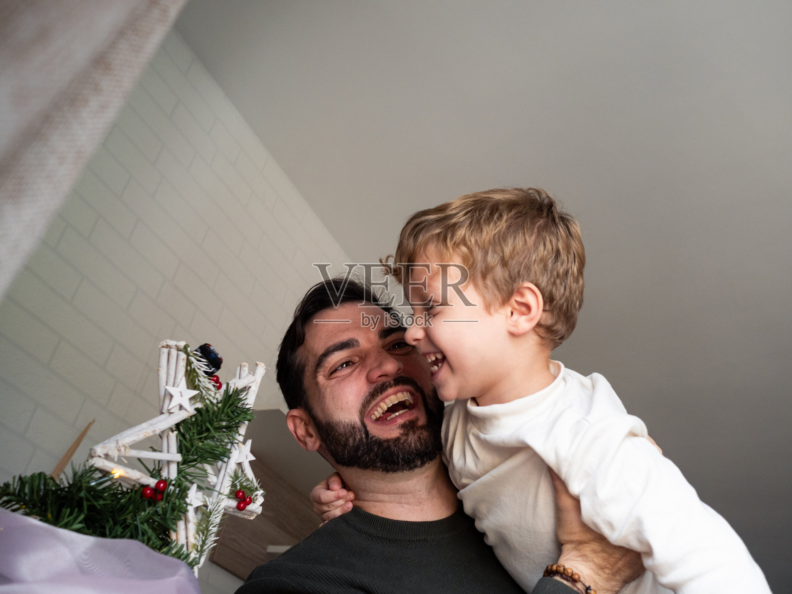 快乐的父亲和儿子一起装饰圣诞树，享受假日时光。照片摄影图片