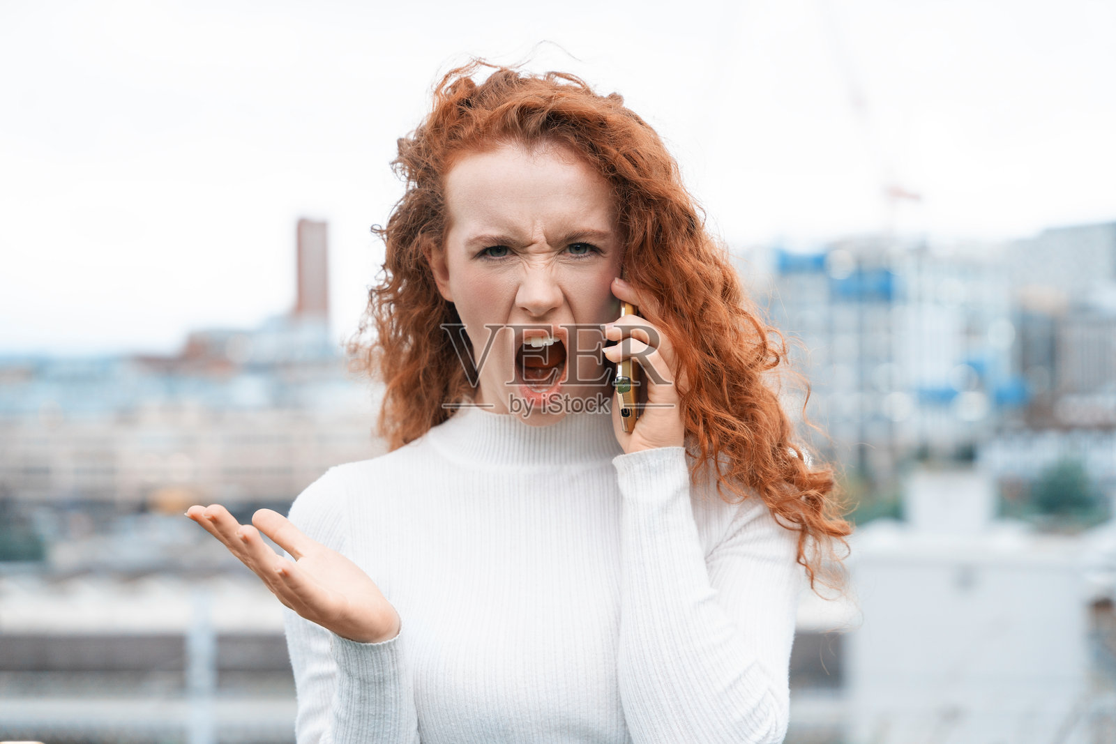 女性在阴天的城市环境中打电话时表达沮丧情绪照片摄影图片