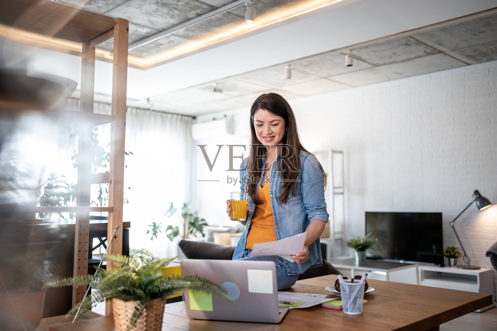 年轻女性在家办公室远程工作，享受橙汁照片摄影图片