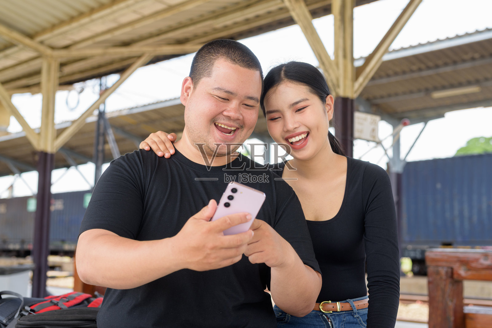 年轻情侣在火车站一起使用手机照片摄影图片