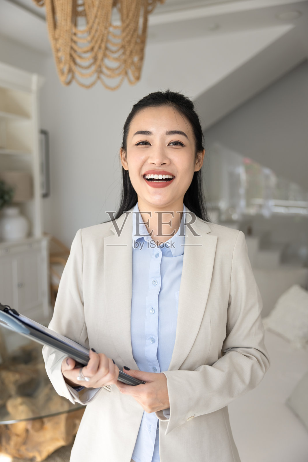 快乐的女性房地产经纪人在现代客厅中摆姿势的肖像照片摄影图片