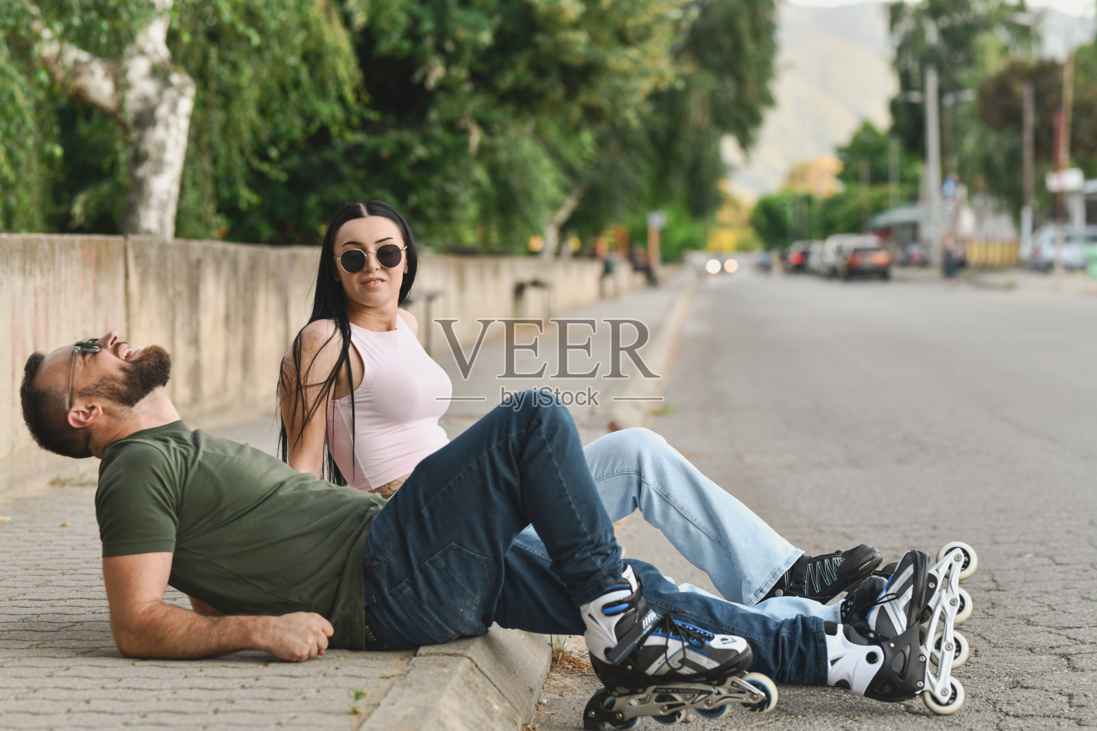 运动情侣在地上放松，穿着滑轮鞋，享受愉快的骑行后轻松聊天。照片摄影图片