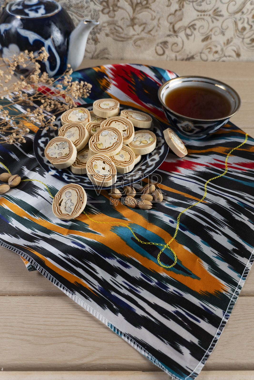 传统乌兹别克茶和哈瓦在伊卡特织物上与开心果一起摆放照片摄影图片