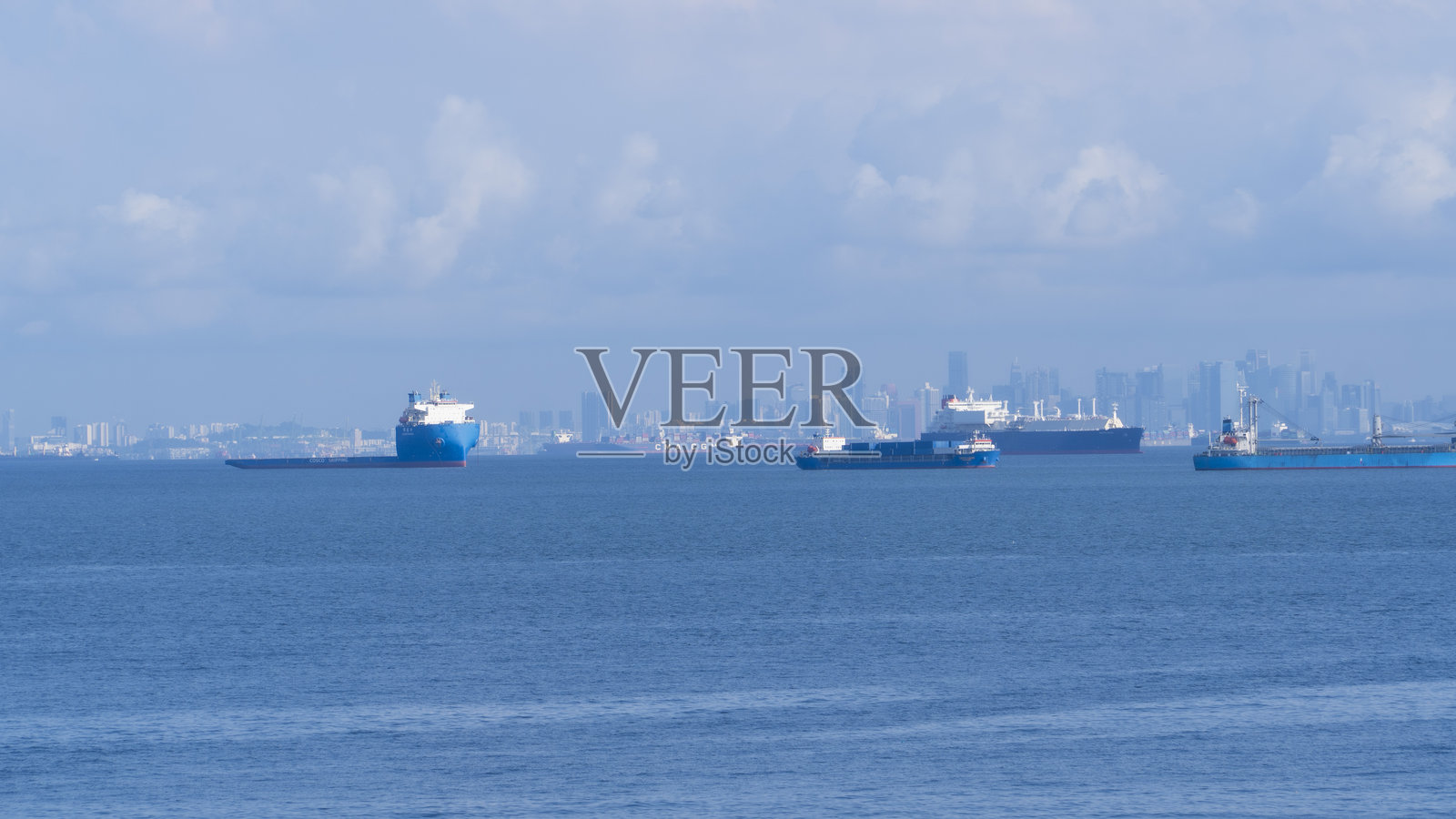 从巴淡岛望向繁忙的新加坡天际线，海峡中停泊着多艘船只。照片摄影图片