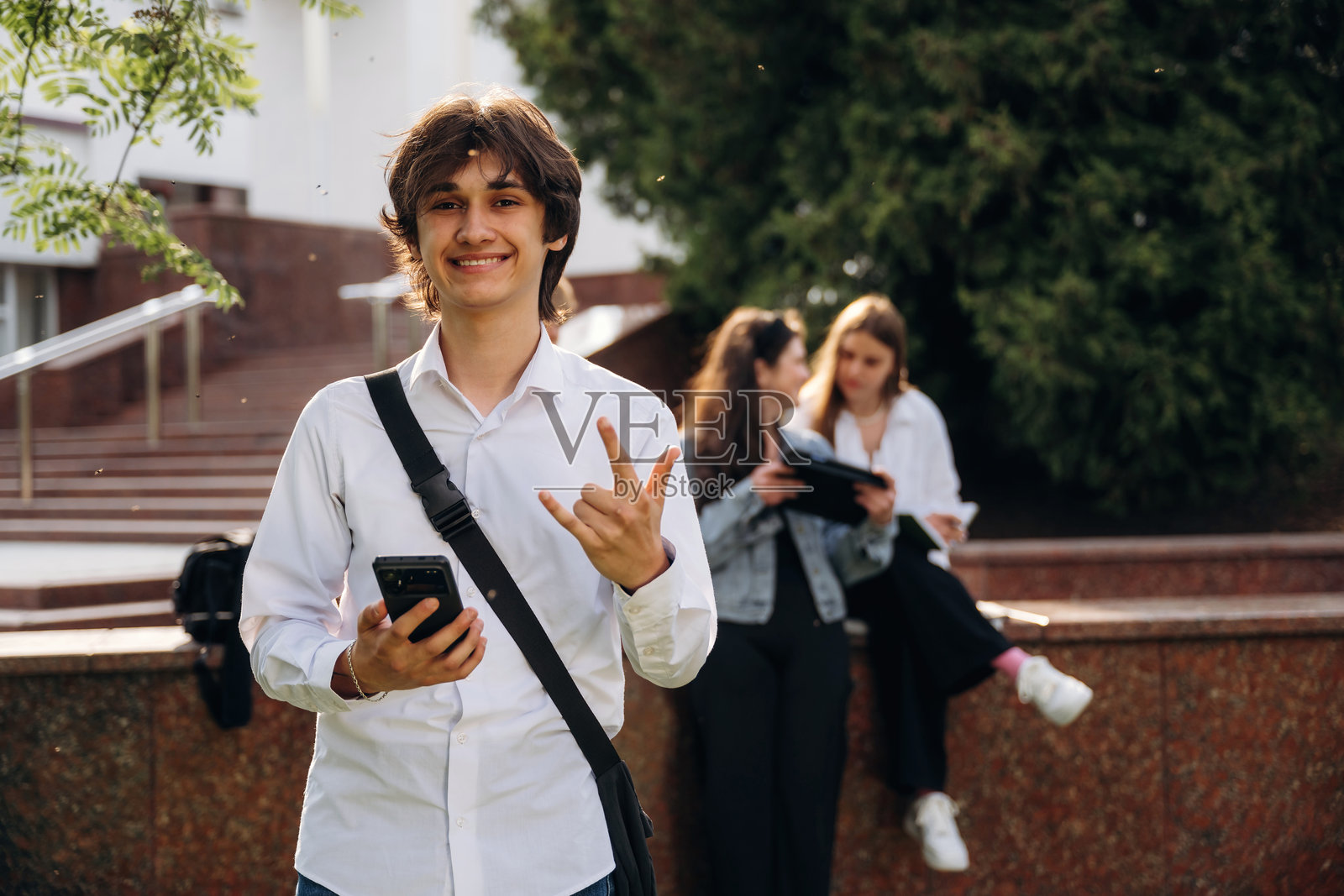 穿着白衬衫、面带积极表情的学生们在大学附近聚在一起。照片摄影图片