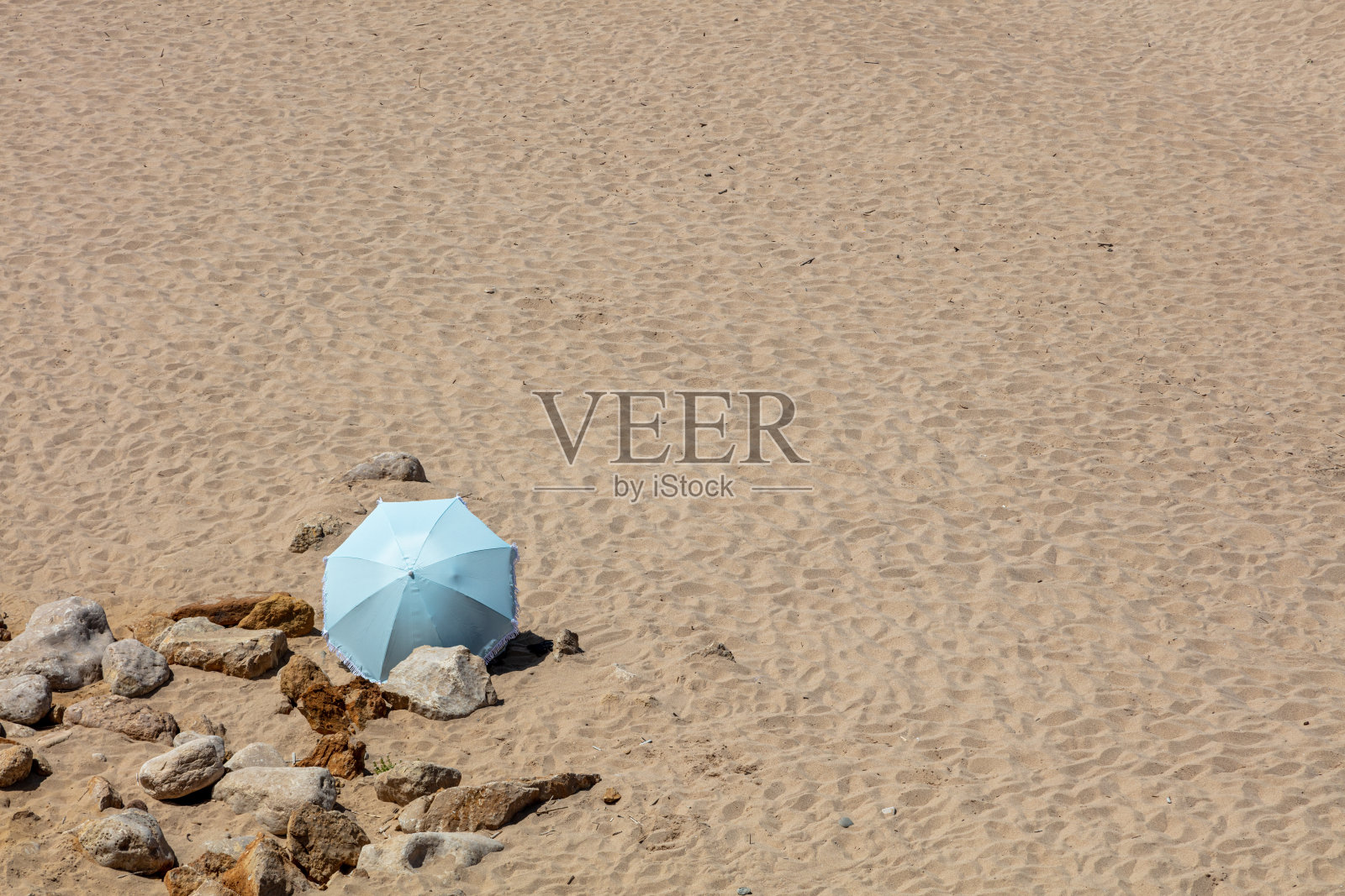 在圣朱利安海滩的沙滩上，蓝色海滩伞伫立着。照片摄影图片