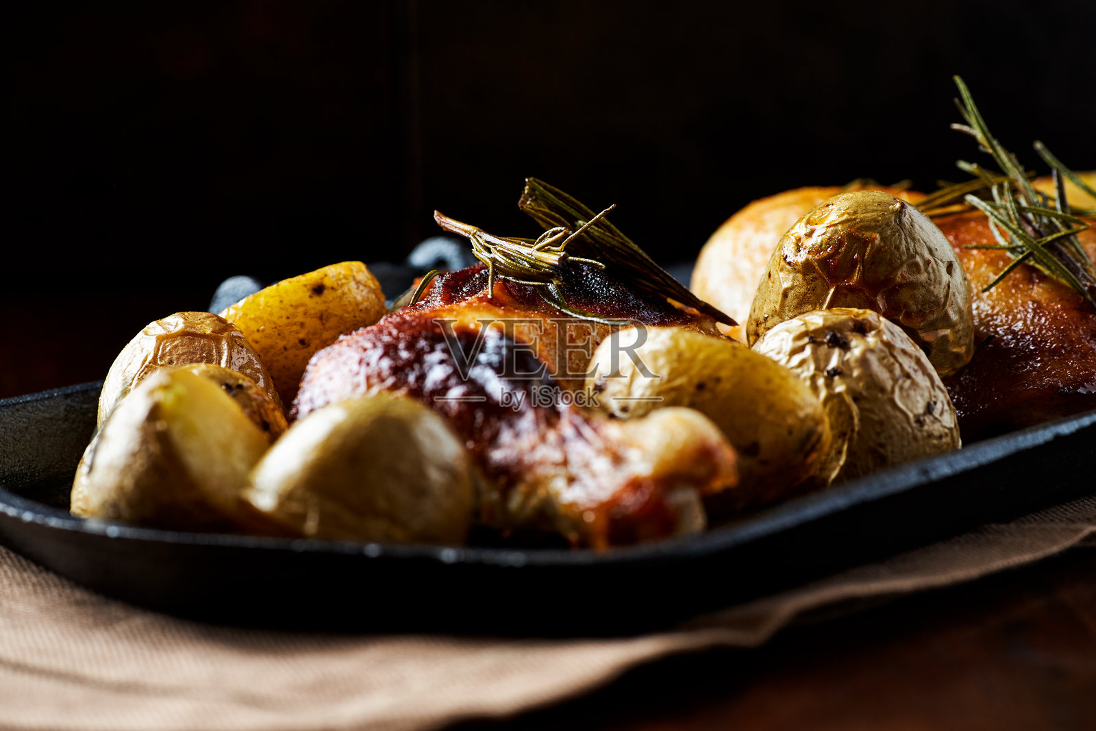 脆皮烤鸡腿配土豆。深色木质背景。特写。照片摄影图片