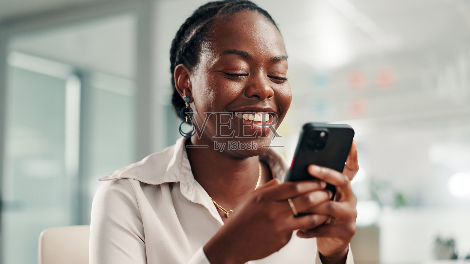 手机、微笑的女商人正在办公室通过社交媒体发短信或留言，笑着看搞笑图片。幽默、沟通和黑人员工在智能手机上浏览网站、移动应用或互联网应用。照片摄影图片