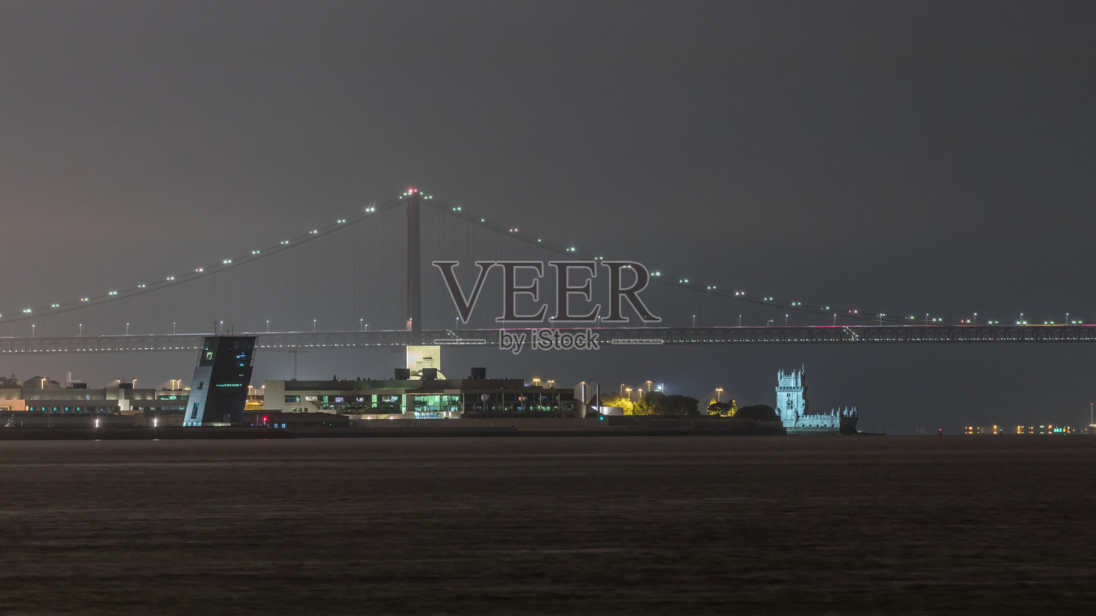 里斯本，葡萄牙的塔古斯河和四月二十五日大桥（Ponte 25 de Abril）在夜间的灯光照耀下。照片摄影图片