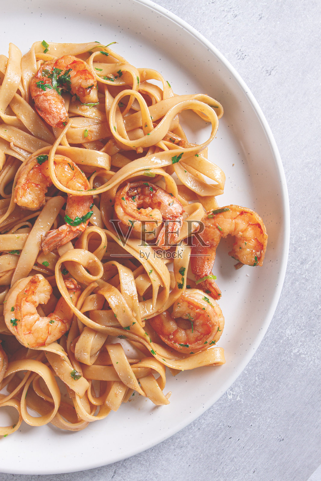 灰色盘子上的意大利宽面条配虾，酱油调味，微辣，近距离特写，叉子在旁。照片摄影图片