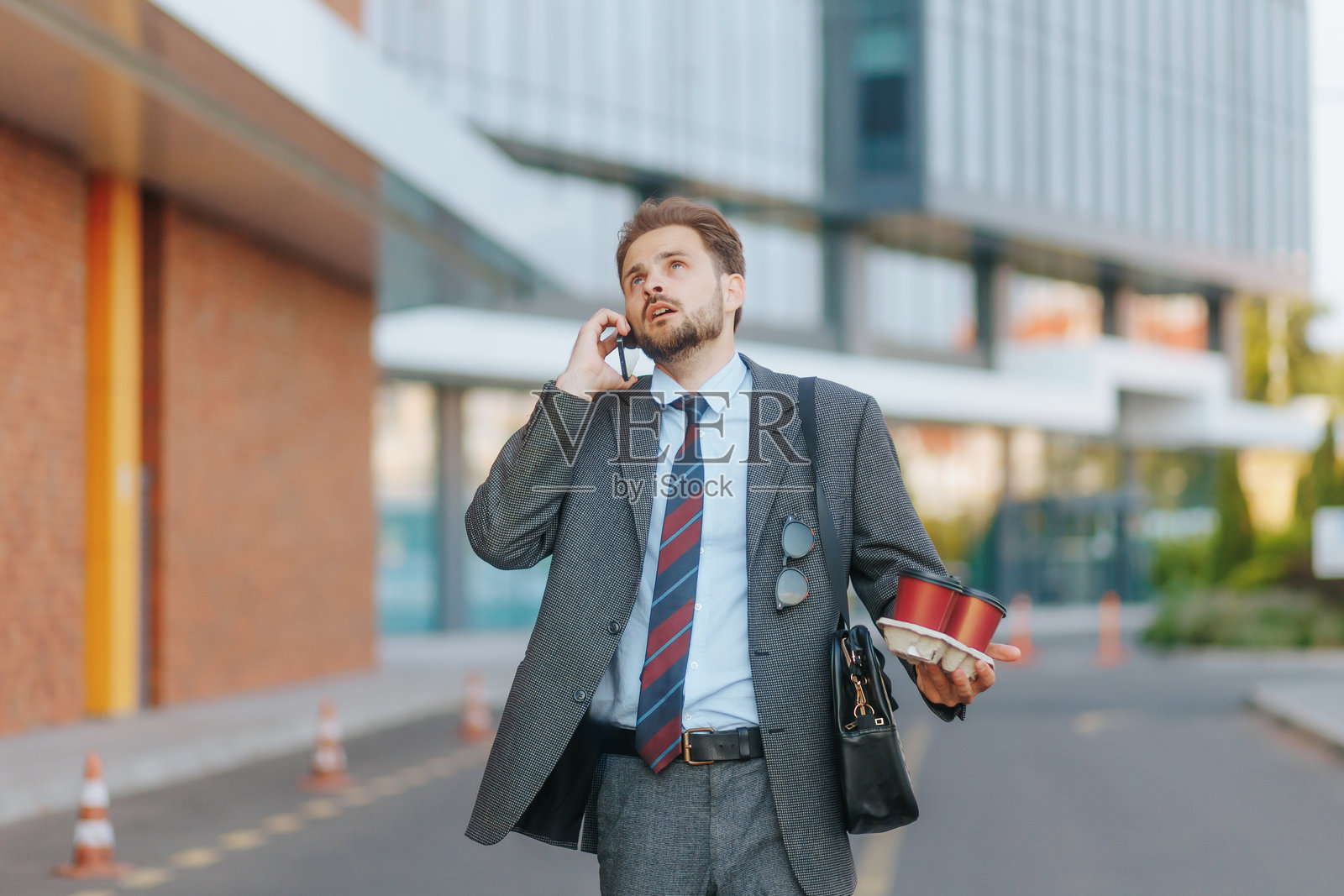 穿着西装的愤怒男子在户外走动并打电话照片摄影图片