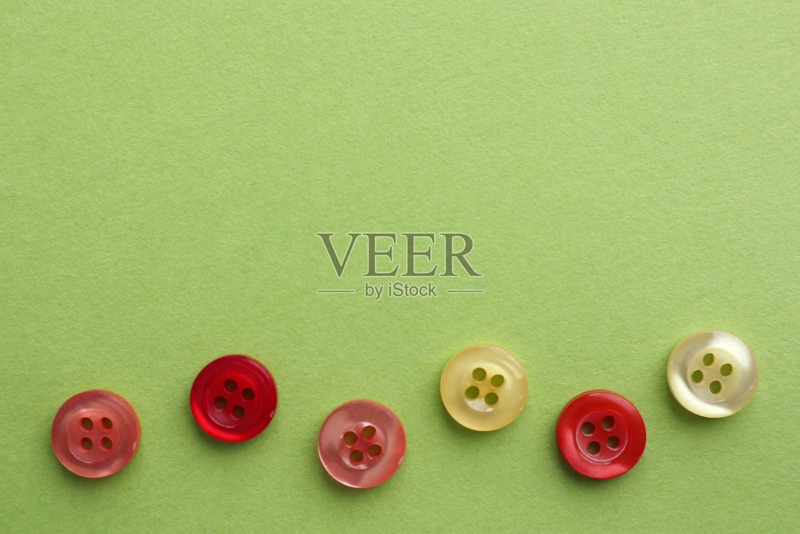 五颜六色的缝纫纽扣，背景为黄绿色。照片摄影图片