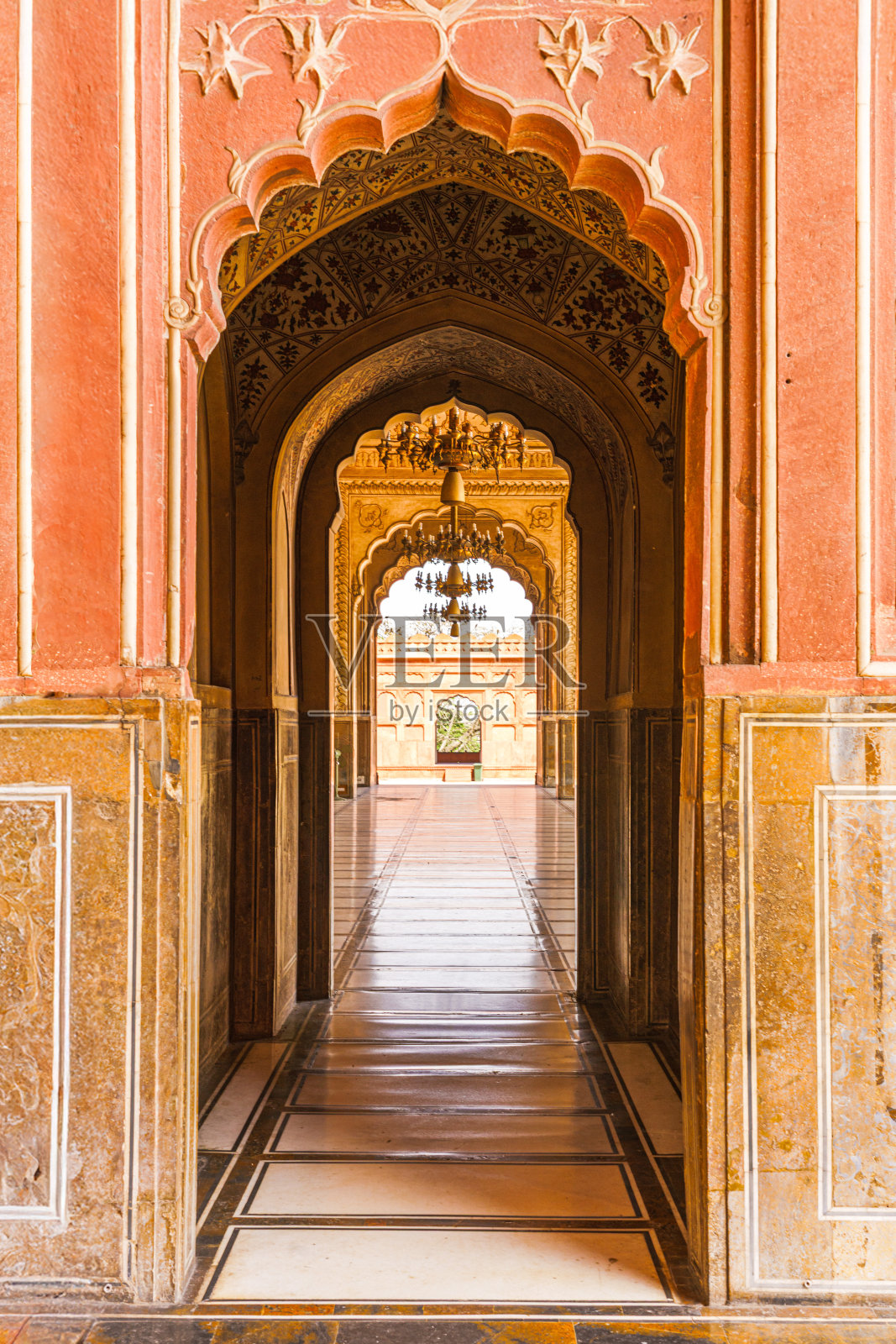 这幅迷人的巴德沙希清真寺内部景观突显了其历史设计的精美细节，金色的色调和优雅的图案吸引着人们的目光穿过宏伟的大厅。照片摄影图片