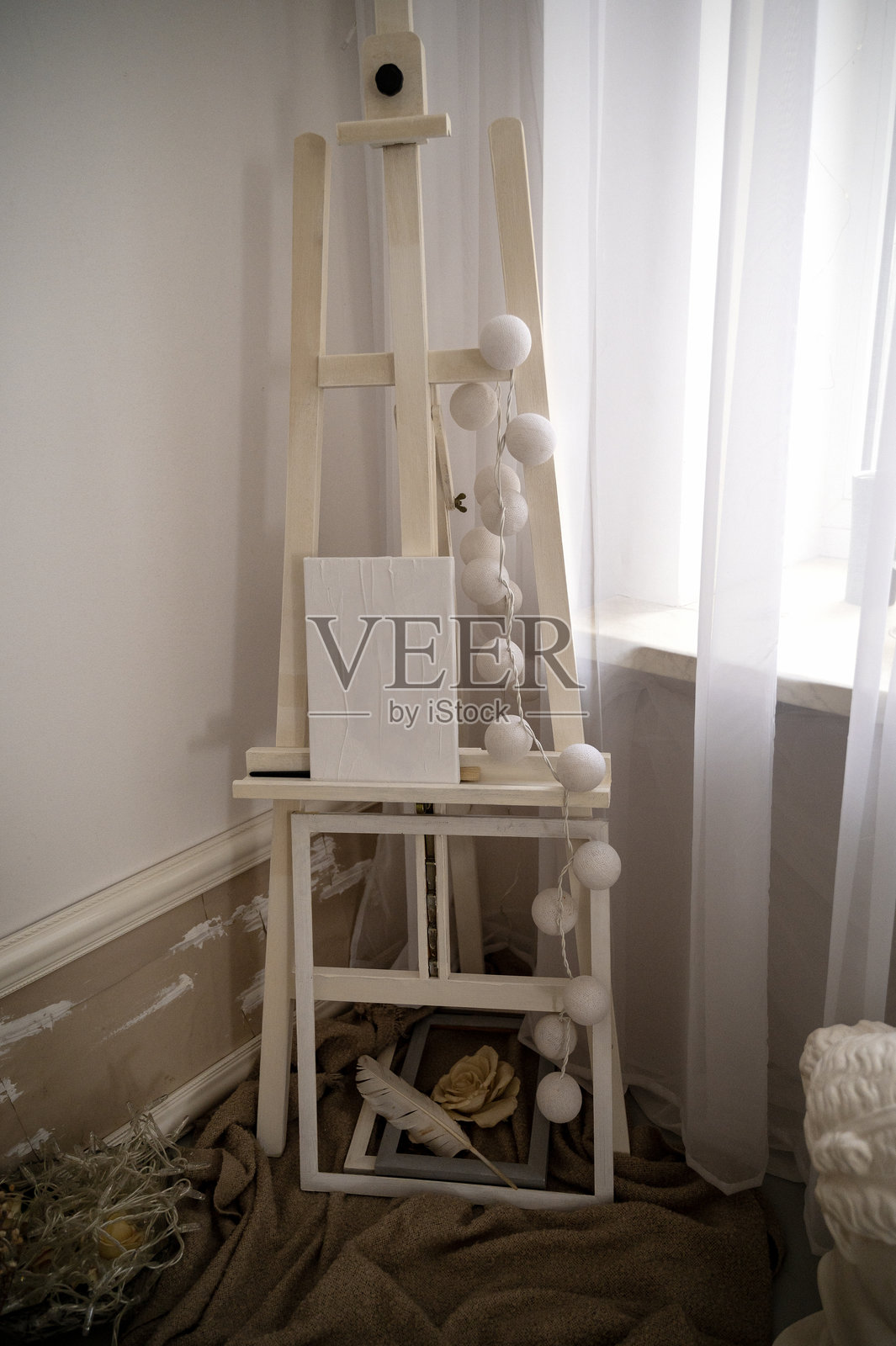 房间里的木制画架。窗边的画架上放着一块干净的白色画布。照片摄影图片