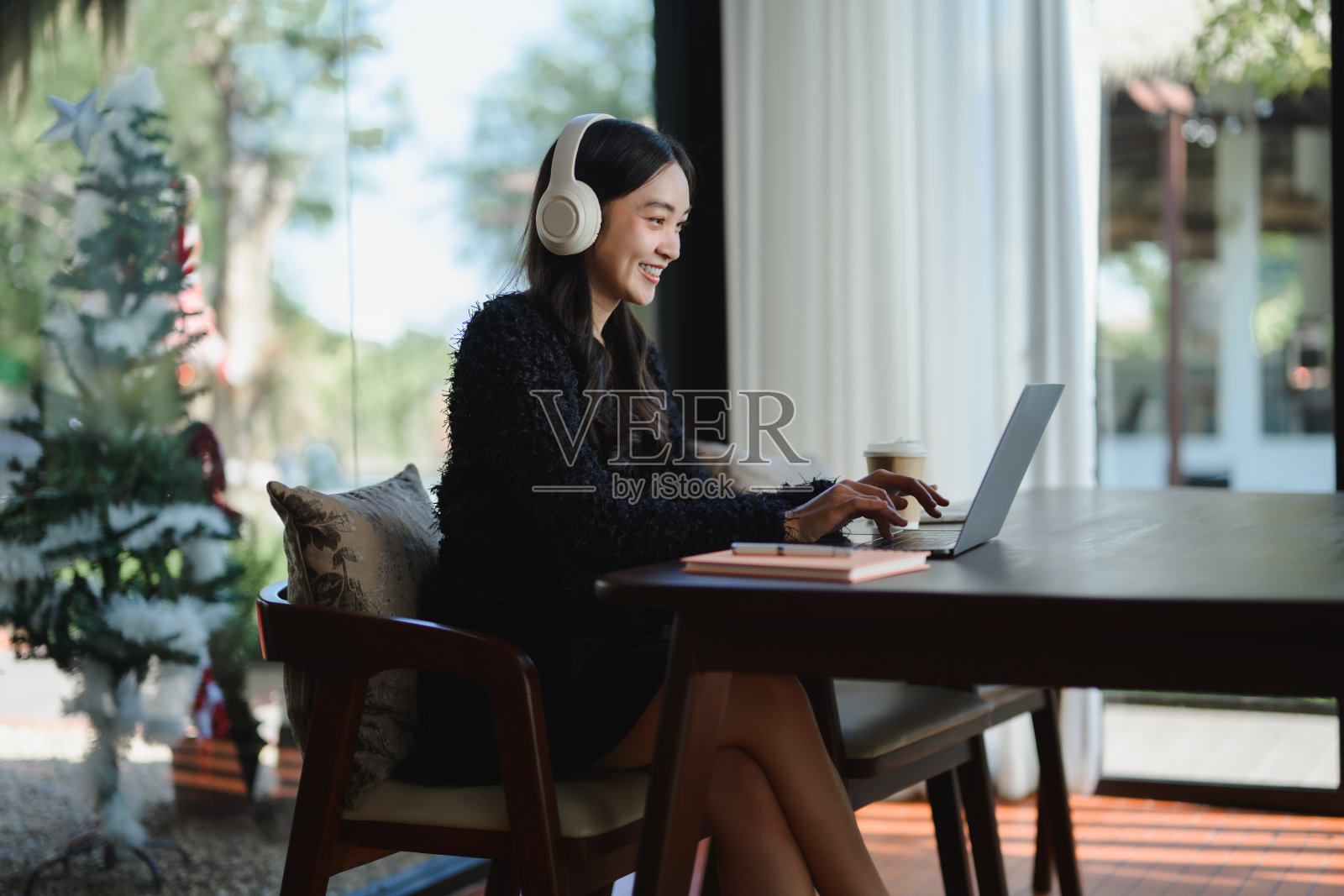 亚洲女商人在圣诞期间使用耳机和笔记本电脑远程工作照片摄影图片