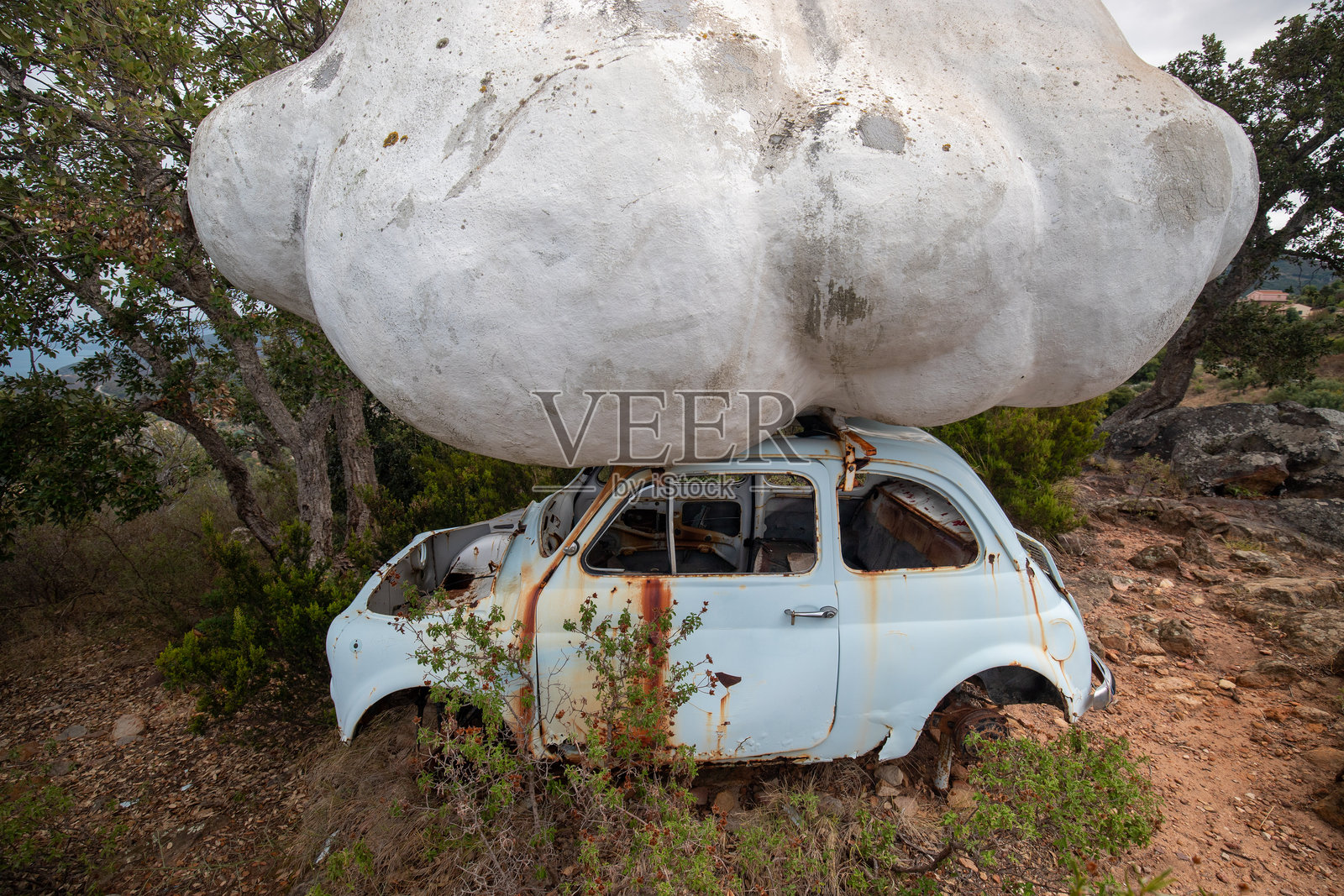 意大利西西里岛 - 2020年9月2日：城市雕塑：石头云朵静静地 resting 在一辆经典的生锈汽车上。照片摄影图片