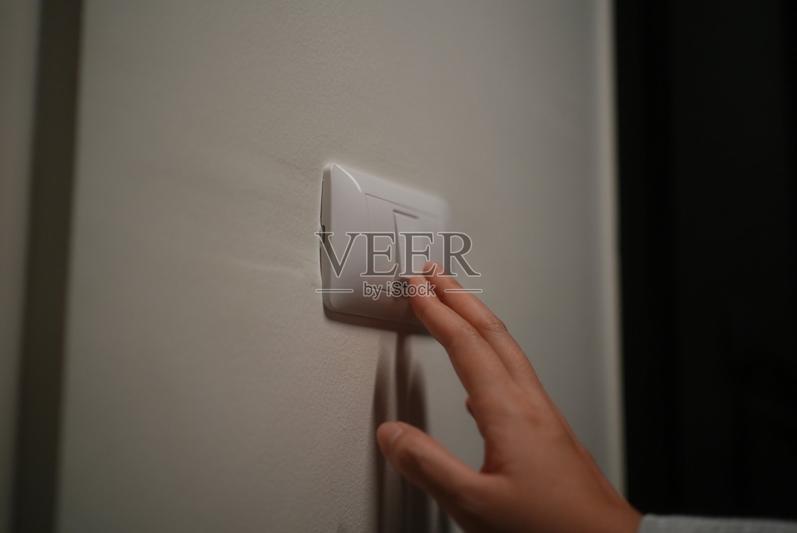 特写镜头：女性用手指按下开关，开启或关闭灯光，以节省电力，养成节约用电的习惯，降低电费，支持环保和可持续发展理念。照片摄影图片