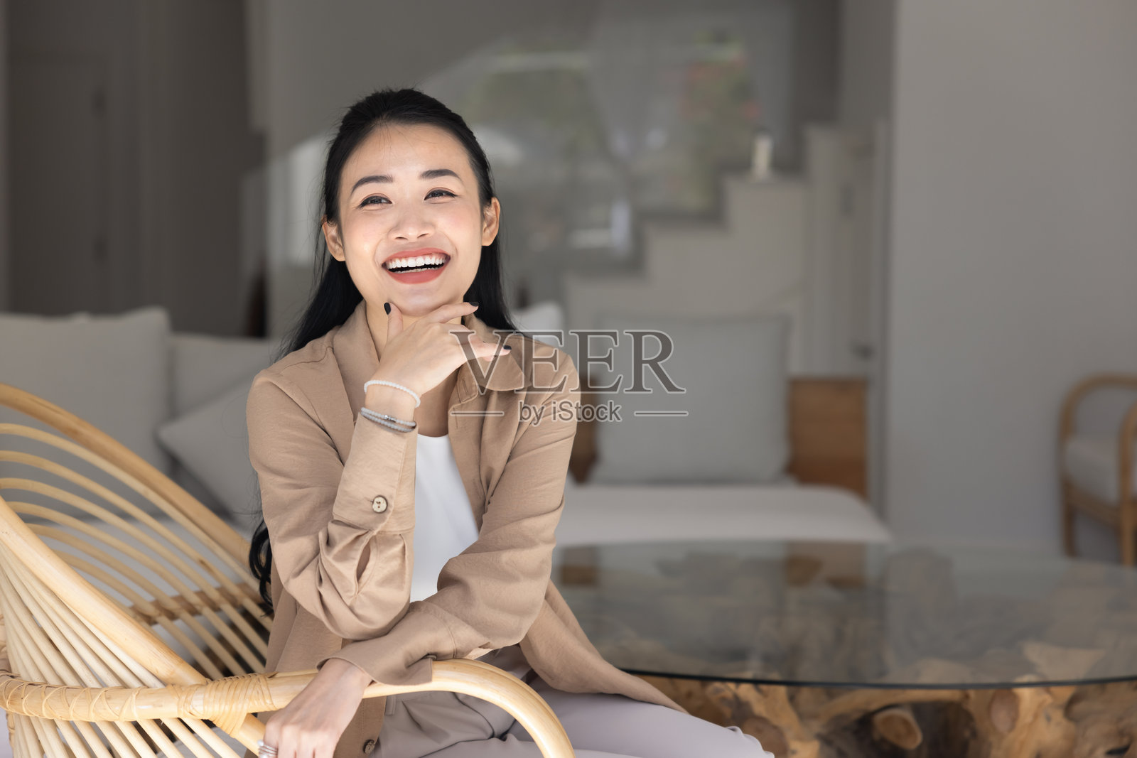 快乐的女人在现代藤椅上放松，坐在客厅里照片摄影图片