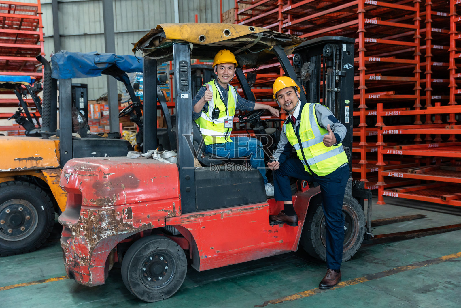 两位亚洲货运场经理在仓库内的叉车上交流照片摄影图片