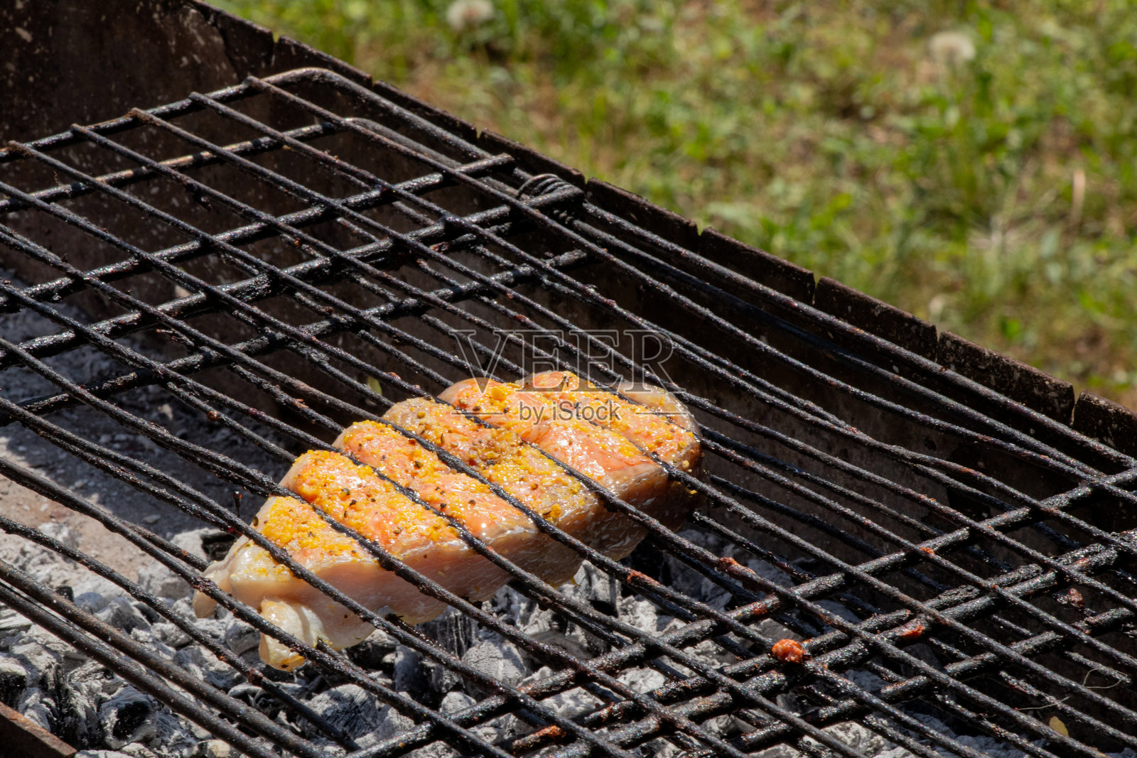 一块调味的三文鱼在炭火烤架上烤制，户外烧烤鱼类。照片摄影图片