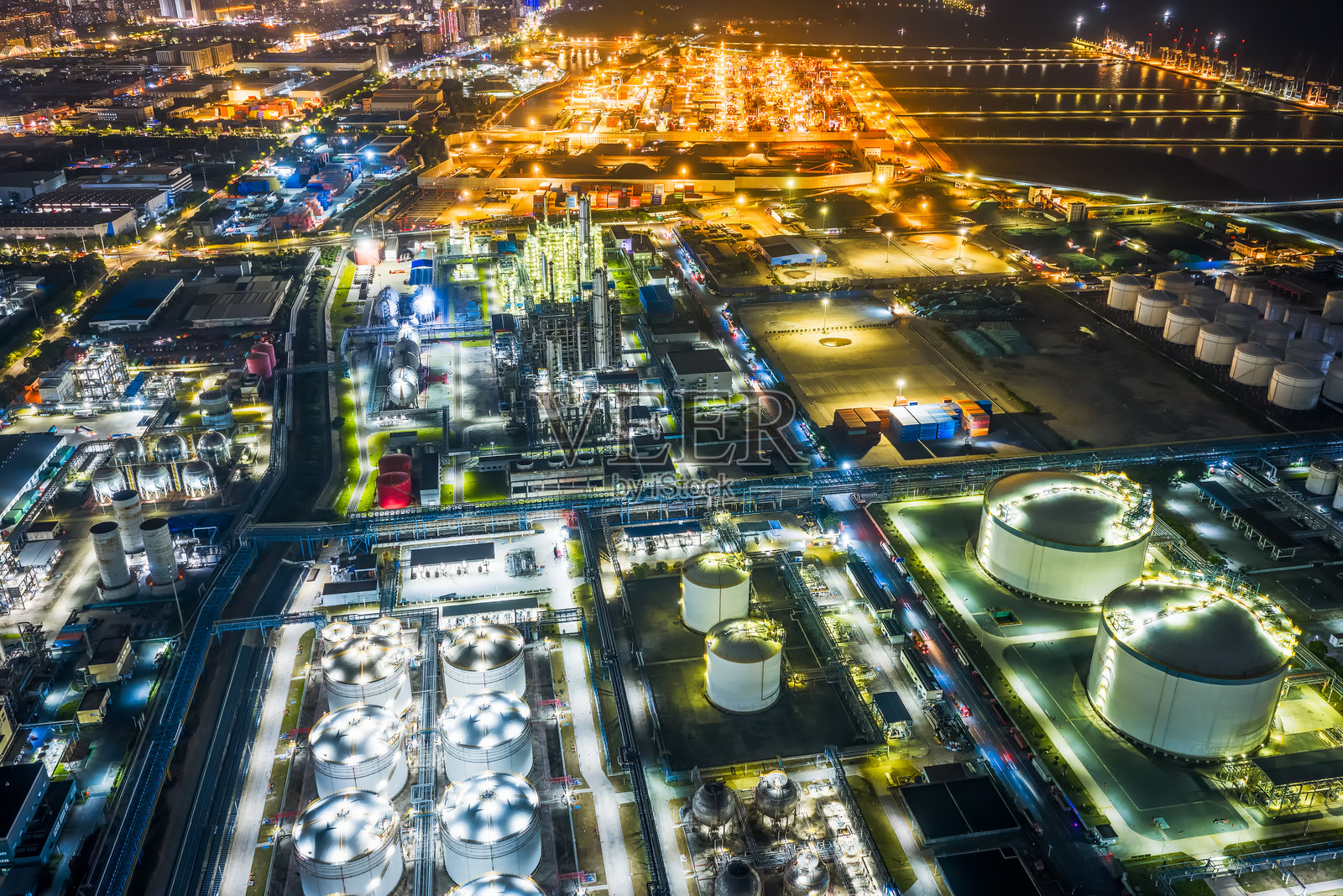 夜间大型工业园区的鸟瞰图，包含石油炼油厂、储油罐和集装箱港口。照片摄影图片