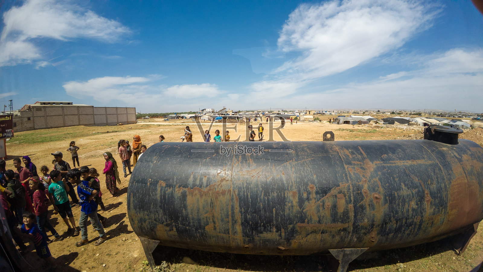 孩子们在乡村环境中围绕水箱聚集照片摄影图片