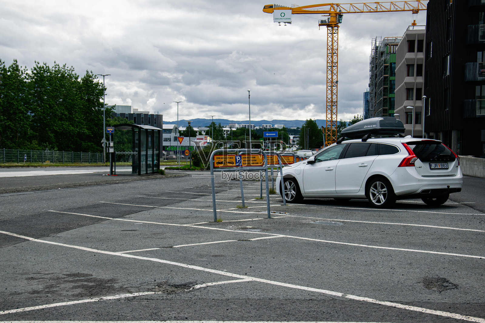 孤独的白色沃尔沃V60停在雷克雅未克的建筑工地旁，周围是城市环境。照片摄影图片