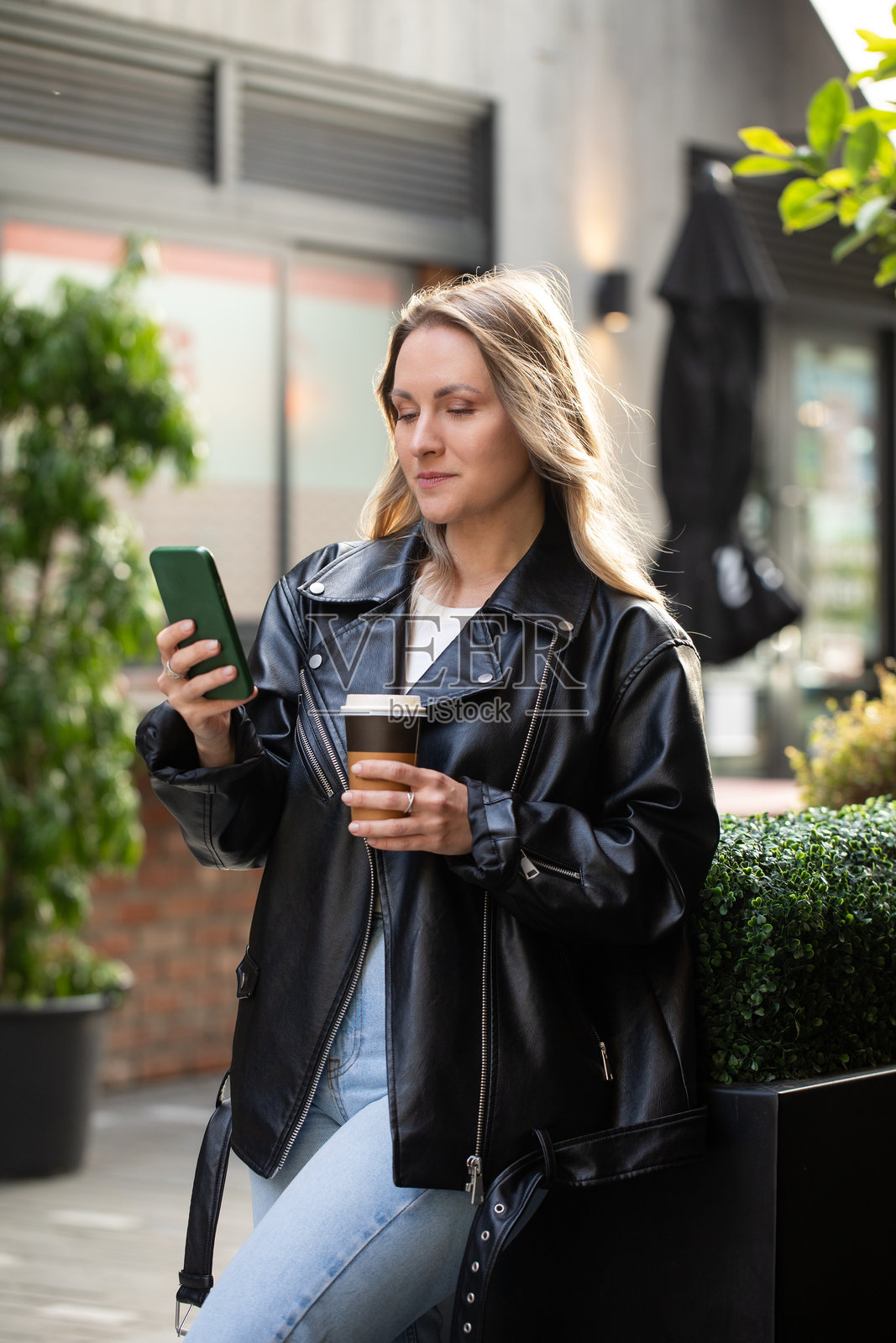年轻的白人女性在城市环境中享受咖啡和智能手机照片摄影图片